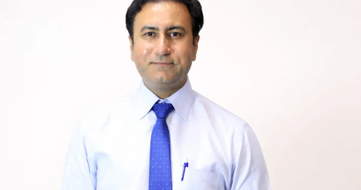 best cancer hospital in Lahore 2026 - A professional headshot of a middle-aged man with dark hair, wearing a light blue dress shirt and a blue patterned necktie against a plain white background.